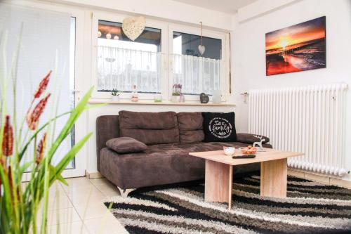 un soggiorno con divano marrone e tavolo di INDIVIDUAL APARTMENTS - Zentrale, ruhige Wohnung in Innenstadt - Küche, Parkplatz, Terrasse, SmartTV, Netflix a Bitburg