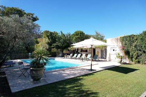 une piscine avec des chaises et un parasol à côté d'une maison dans l'établissement LS1-448 - Sounja, à Tarascon