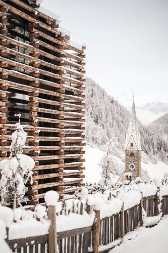 a church covered in snow next to a fence at Hotel Jaufentalerhof in Racines