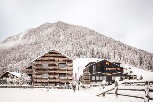 a log cabin in the snow in front of a mountain at Hotel Jaufentalerhof in Racines