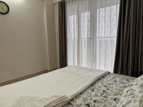 a bed in front of a window with a clock at Memmsta Blooming Bird Guruvayur in Guruvāyūr