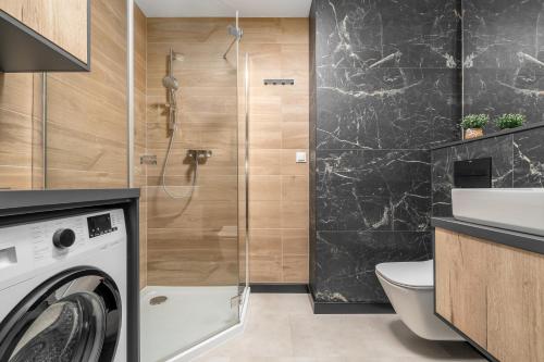 een badkamer met een wasmachine en een douche bij Apartament Flaming Hanza Tower in Szczecin