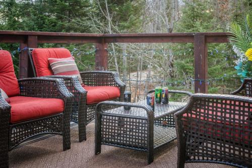 three wicker chairs and a table on a patio at Chalet au Boisé in Saint Come
