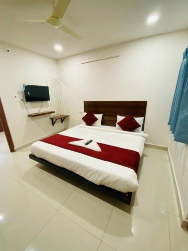 a bedroom with a bed with a red and white blanket at HK Guest Rooms in Guntūr