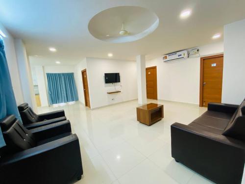 a living room with two black chairs and a tv at HK Guest Rooms in Guntūr