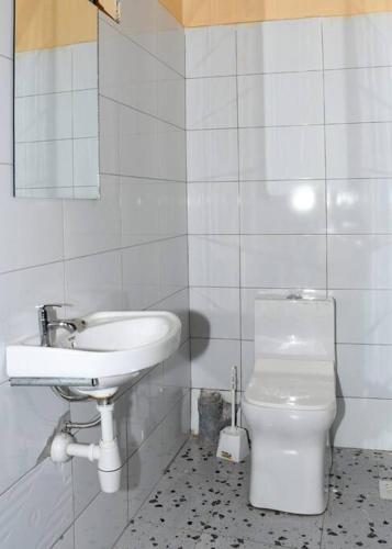 a white bathroom with a sink and a toilet at Airport Bliss House in Kisumu