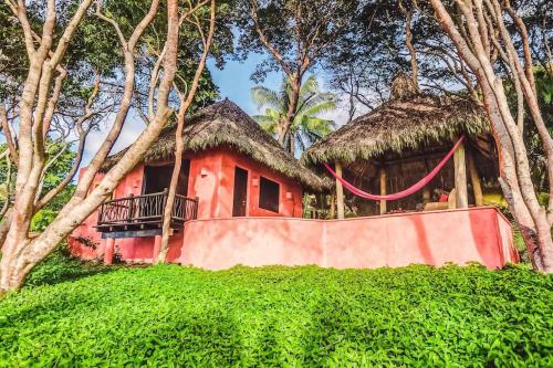 a small red house with a thatch roof at Casa Mis Amores in Sayulita