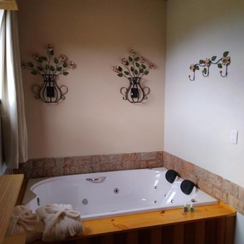 a bath tub in a bathroom with two vases on the wall at Recanto KAIRÓS in Visconde De Maua