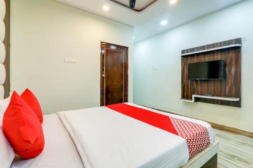 a bedroom with a bed with red pillows and a tv at Hotel Navya Grand in Patna