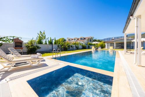 a swimming pool with two chairs and a house at Villa Tolga in Dalyan