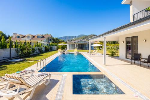a swimming pool with two chairs and a house at Villa Tolga in Dalyan