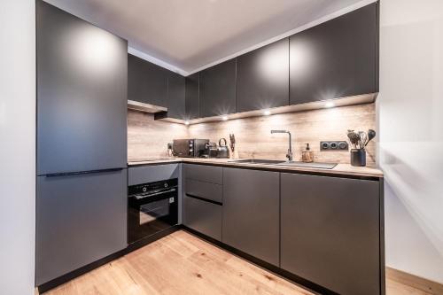 - une cuisine avec des placards noirs et un évier dans l'établissement Apartment Gentiana, Les Gets - by EMERALD STAY, aux Gets