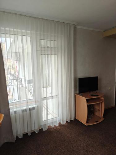 a room with a television and a window with curtains at Noviz Hotel in Plovdiv