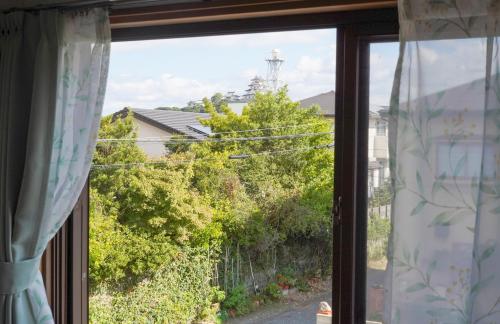 a window with a view of a house at 一棟貸切AKARIYA Home in Karatsu