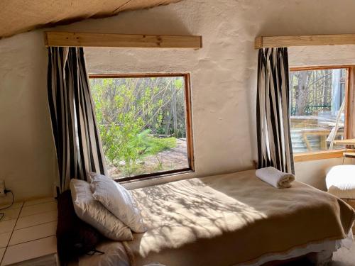 a bed in a room with a large window at UnderHill Farm in Klipkraal