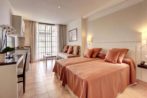 a bedroom with a large bed and a kitchen at Grupotel Club Menorca in Son Xoriguer