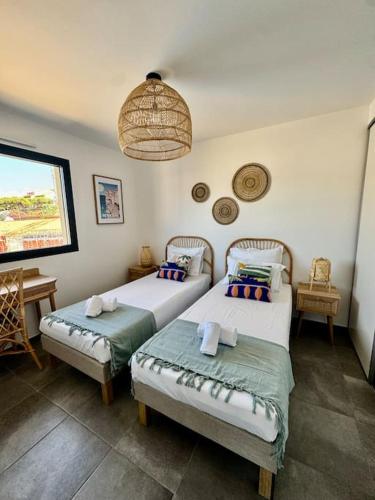 a bedroom with two beds and a pendant light at Magnifique appart T3 vue mer in Propriano