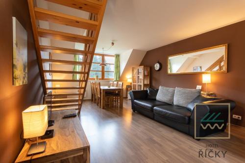 salon z czarną skórzaną kanapą i schodami w obiekcie Apartmány pod Zakletým - Hotel Říčky w mieście Říčky
