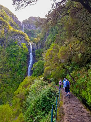 a group of people walking down a path near a waterfall at Favinha Rooftop in Machico