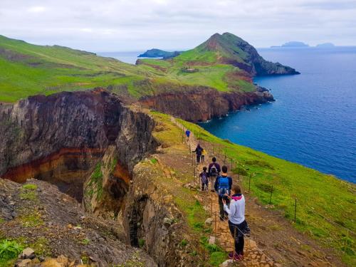 a group of people walking on a cliff near the ocean at Favinha Rooftop in Machico