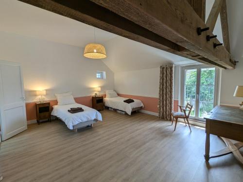 une chambre avec deux lits et une grande fenêtre dans l'établissement La Maison Cornon, à Trumilly