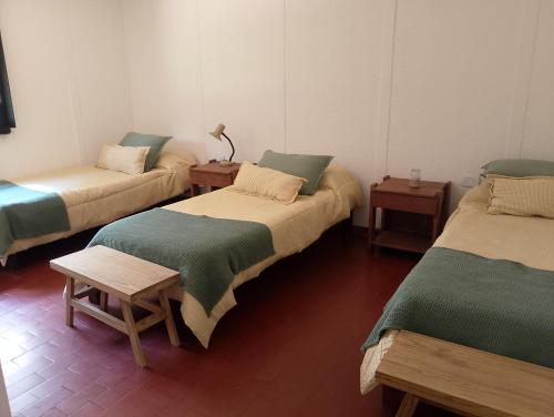 a room with three beds and two tables at Bayas Coloradas, San Lorenzo, Salta in San Lorenzo