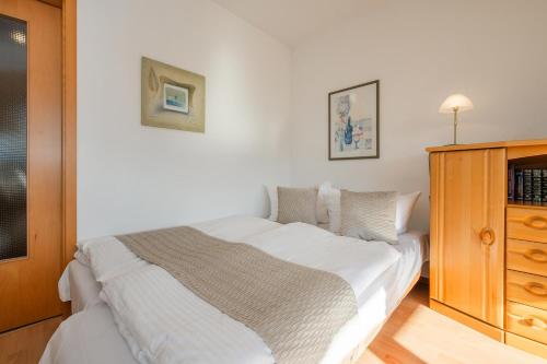 een slaapkamer met een wit bed en een houten kast bij Düneneck 32 in Zempin