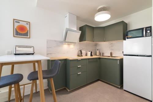 une cuisine avec des armoires vertes et un réfrigérateur blanc dans l'établissement Houat - studio lumineux, à Vannes