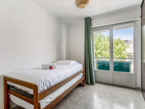 une chambre avec un lit et une grande fenêtre dans l'établissement Charmant appartement dans le Panier, à Marseille