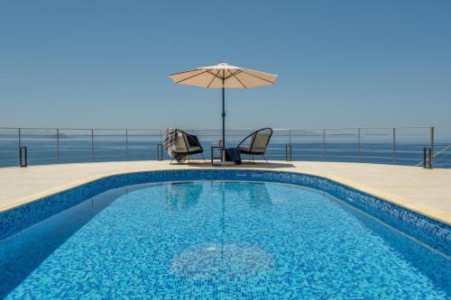 basen z parasolem, stołem i krzesłami w obiekcie Villa Hemera ocean view private heated pool w mieście Chorafakia