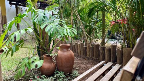 two brown vases sitting next to a wooden bench at Chalés Calima in Lençóis