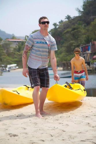 a man standing on the beach next to a yellow kayak at Casas Garcia in Yelapa