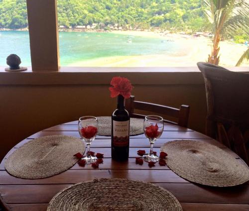 a table with a bottle of wine and two glasses at Casas Garcia in Yelapa