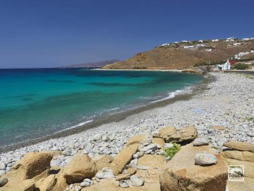 a beach with rocks and the blue water at Mykonos Seaview Nests - Tourlos Getaways in Tourlos