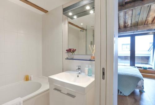 a white bathroom with a sink and a bath tub at Wild Roses Serviced Apartments - ExCel Warehouse 1 in London
