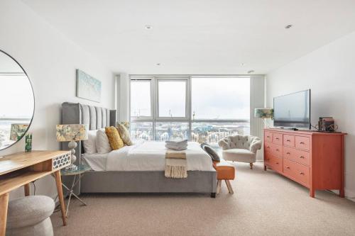 a bedroom with a bed and a desk and a tv at Serene Waterfront Rooms - ExCel in London