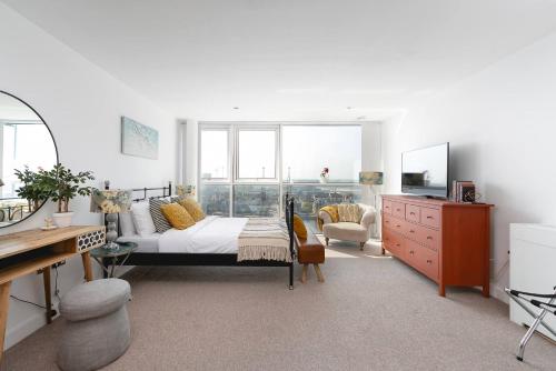 a bedroom with a bed and a dresser and a desk at Serene Waterfront Rooms - ExCel in London