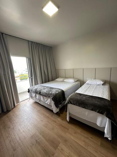 two beds in a room with a window at Rio Jordao Hotel in Siderópolis