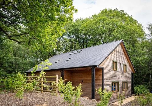a wooden barn with a gambrel roof at Errwood, woodland lodge with hot tubs for 14 in Oakamoor