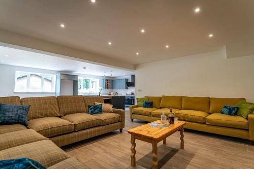 a living room with two couches and a table at Errwood, woodland lodge with hot tubs for 14 in Oakamoor