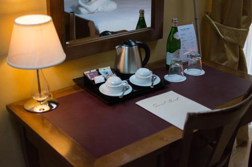 a table in a hotel room with a lamp and a tray with cups and coffee at Relais La Colombara Spa & Wellness in Travo