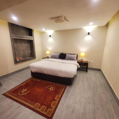 a bedroom with a bed and a window and a rug at The Garden Hotel in Islamabad