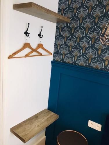 Cette chambre comprend deux cintres en bois et un mur bleu. dans l'établissement Superbe appartement cosy aéroport Orly & Ligne 14 Paris avec terrasse, à Athis-Mons