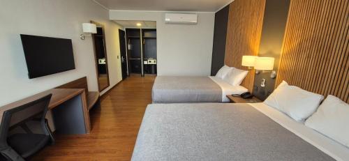 a hotel room with two beds and a flat screen tv at Hotel Diego de Almagro La Serena Express in La Serena