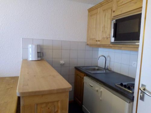 une petite cuisine avec un évier et un micro-ondes dans l'établissement Appartement spacieux à Méribel, accès pistes, animaux admis - FR-1-355-162, à Les Allues