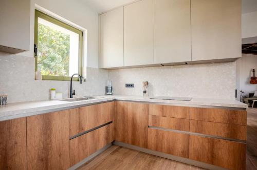 a kitchen with wooden cabinets and a window at Villa Anthos - Superb panoramic sea and hill views with private pool in Gavalochori
