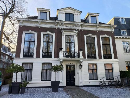 a large white house with a black door at Blue Wave Stay - Free Parking in Scheveningen