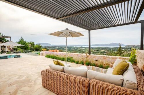 a patio with a couch and an umbrella at Villa Anthos - Superb panoramic sea and hill views with private pool in Gavalochori