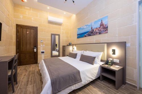 a bedroom with a king sized bed and a desk at C4 Retreats by Georges Boutique Living in Xagħra