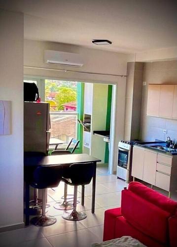 uma cozinha e sala de estar com uma mesa e um sofá vermelho em Studio para locação Pereque-Açu em Ubatuba